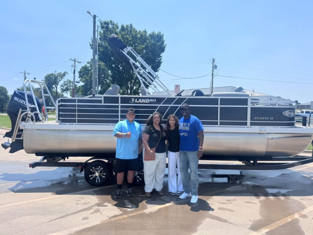 Happy customers standing in front of their brand new 2026 Landau Fishing Tritoon accompanied by a Toons Grand Lake Employee